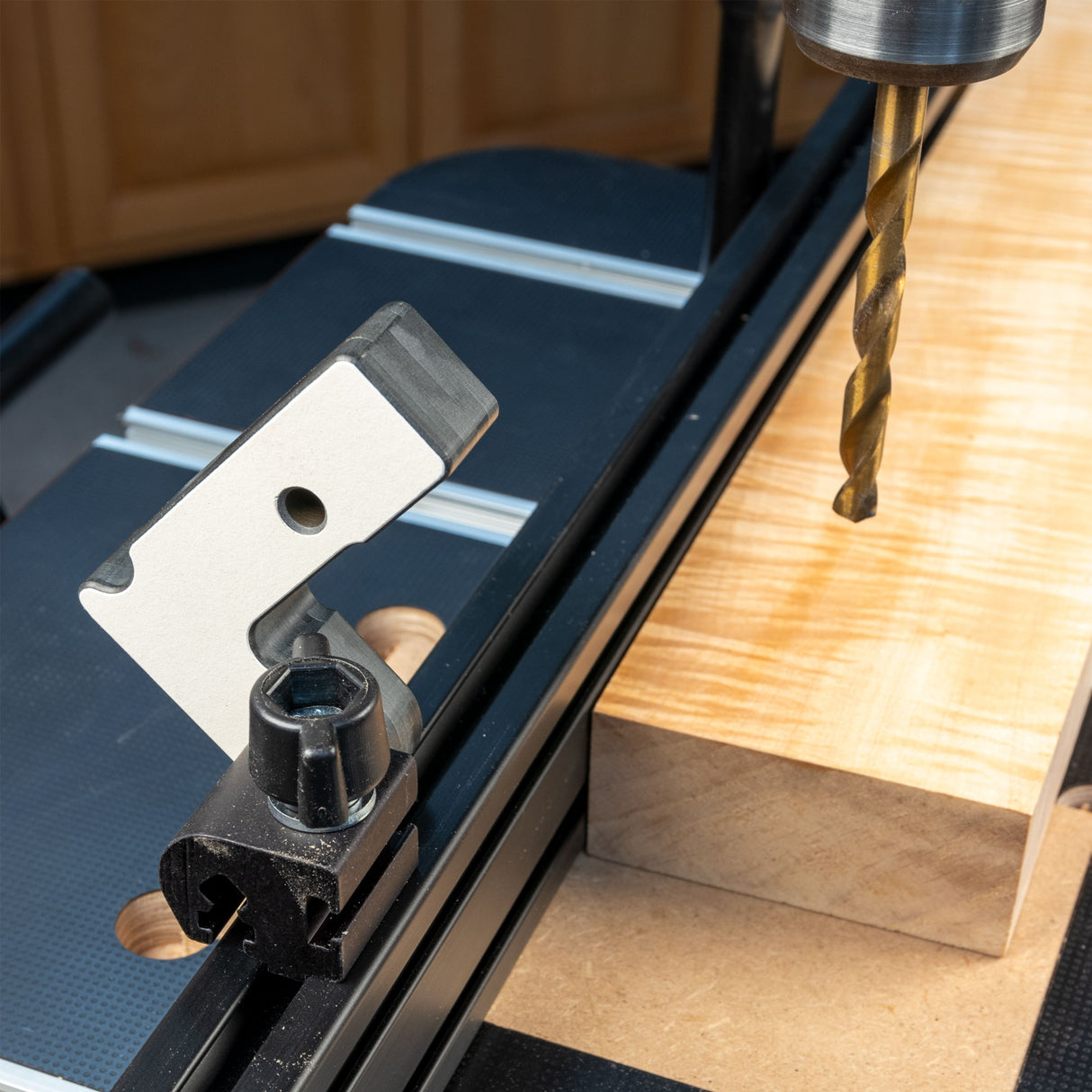 Woodworking drill press setup with T-track stop block and wood block on table