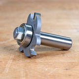 Close-up of a woodworking router bit with bearing on a wood surface