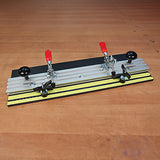 Adjustable woodworking jig with red handle clamps on a wooden workbench