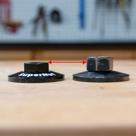 Two woodworking router table nuts side by side, showing height difference with red arrow