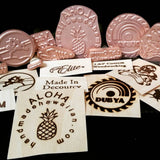 Custom woodworking branding irons and engraved wooden logo samples displayed together.