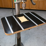 Drill press table with T-tracks and insert for woodworking, mounted in a workshop