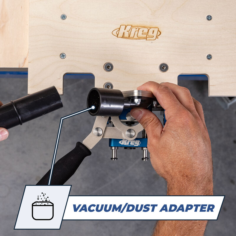 Vacuum dust adapter being connected to woodworking jig beneath wooden workbench.