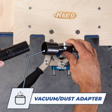 Vacuum dust adapter being connected to woodworking jig beneath wooden workbench.
