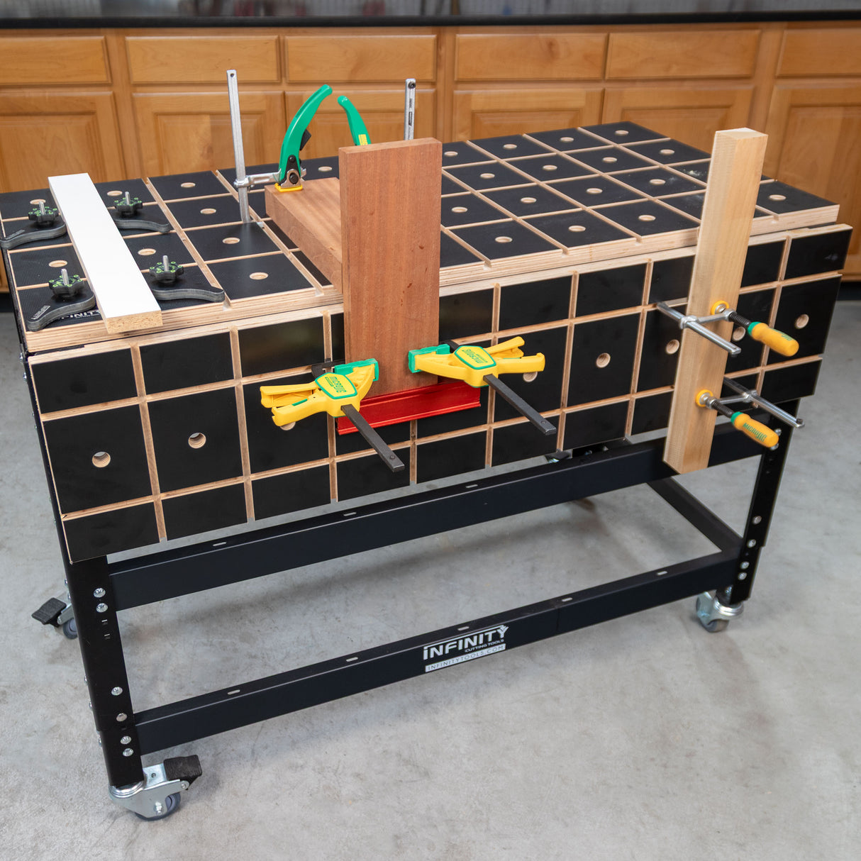 Woodworking workbench with grid top and multiple clamps holding wood pieces in workshop