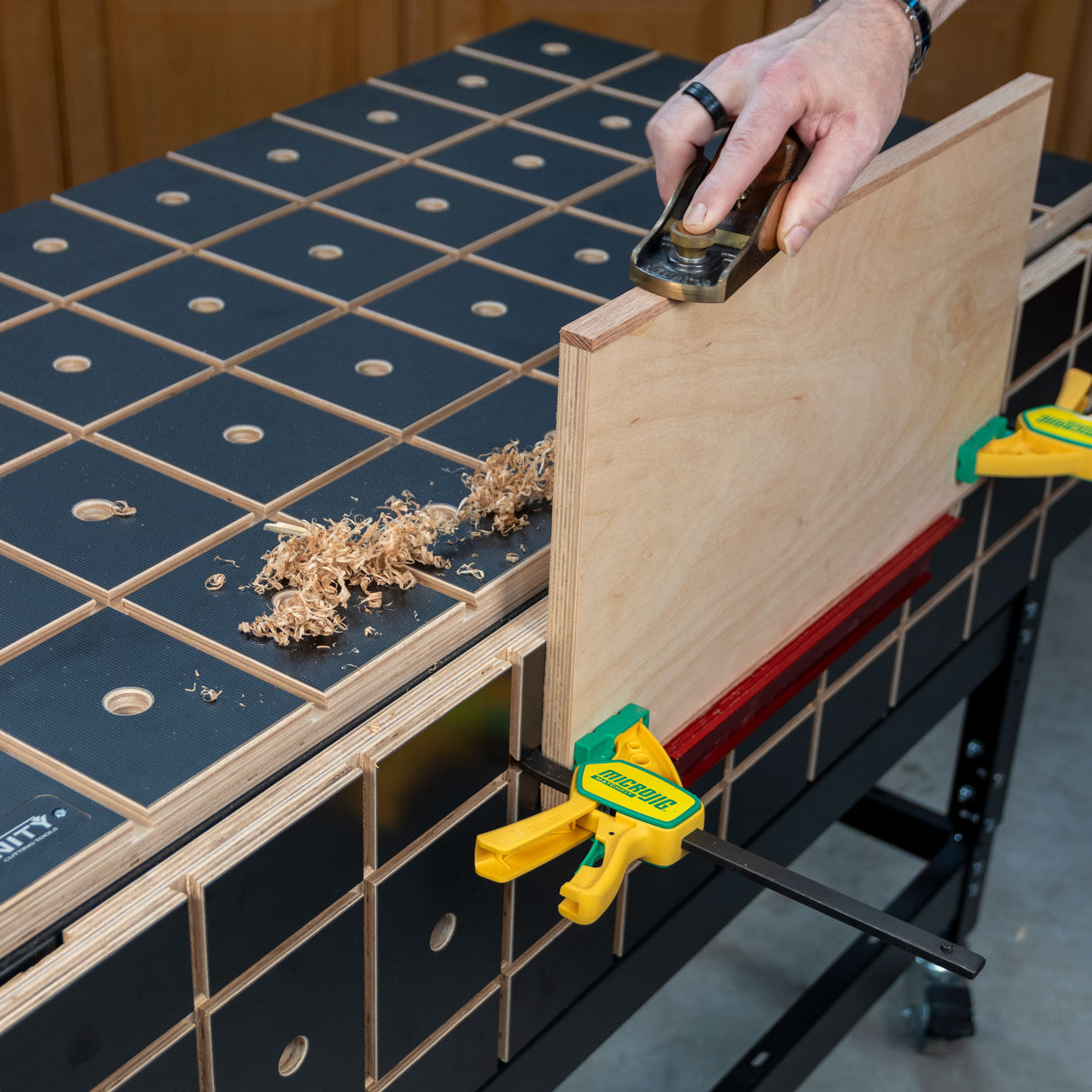 Wood panel clamped to a woodworking bench while being planed by hand