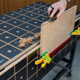 Wood panel clamped to a woodworking bench while being planed by hand