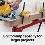 Quick-release woodworking clamps securing a large board on a workbench with a circular saw in use.