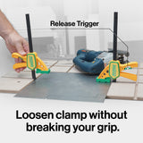 Quick-release woodworking clamps securing metal sheet on workbench with power tool nearby