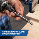 Hand holding a drill with carbide-tipped mortise cutter, woodworking tool in workshop setting