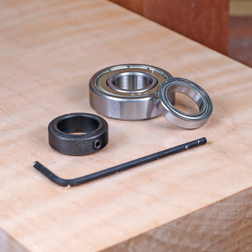 Router bit bearing kit with bearings, collar, and hex key on a wooden workbench