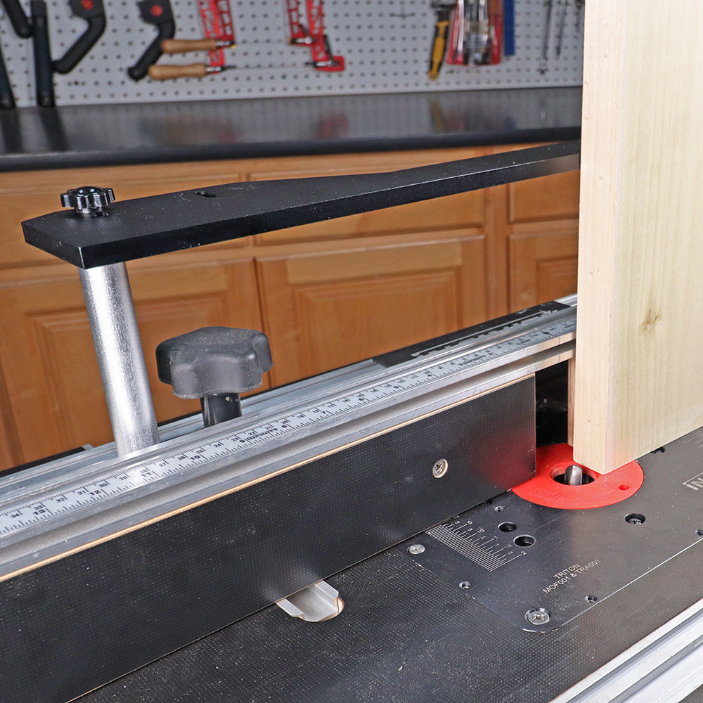 Woodworking router table setup with fence, measuring scale, and vertical push block in use