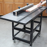 Woodworker using a router table to shape a wooden board in a workshop setting