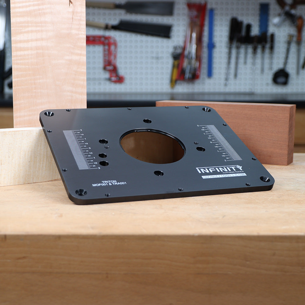 Router table insert plate with measurement markings on a woodworking bench, workshop tools in background.