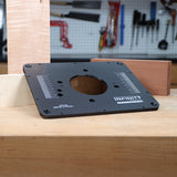 Router table insert plate with measurement markings on a woodworking bench, workshop tools in background.