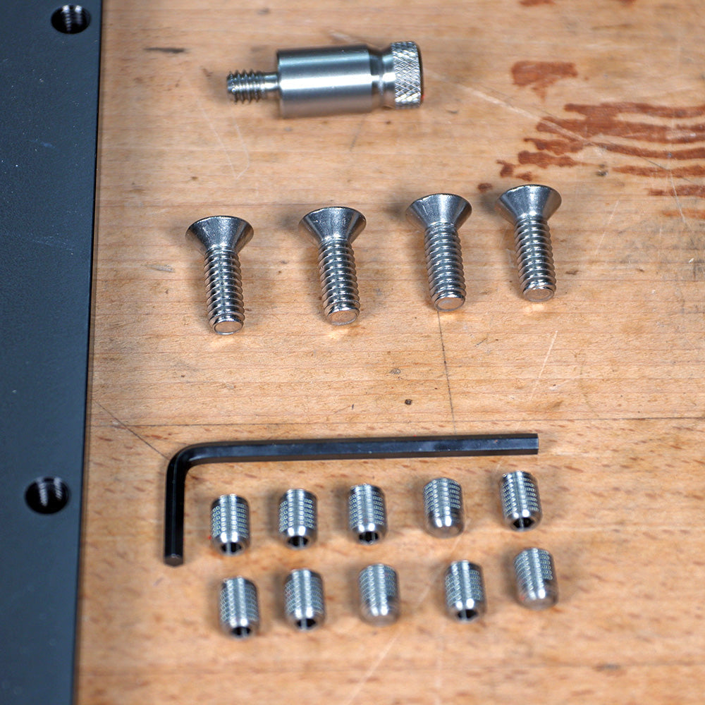 Assorted metal screws, dowel pin, hex key, and set screws on a woodworking bench