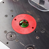 Router table plate with red insert ring and installed router bit, woodworking tool closeup