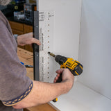 Using a shelf pin jig and drill to create evenly spaced holes in a cabinet