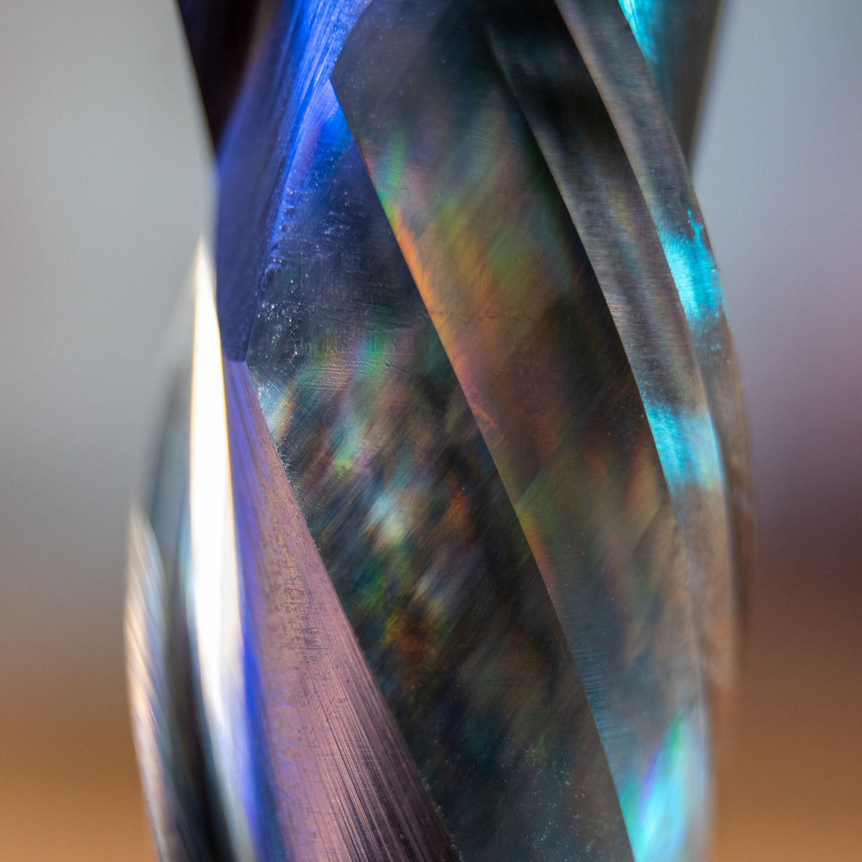 Close-up of a spiral compression router bit with reflective, sharp cutting edges