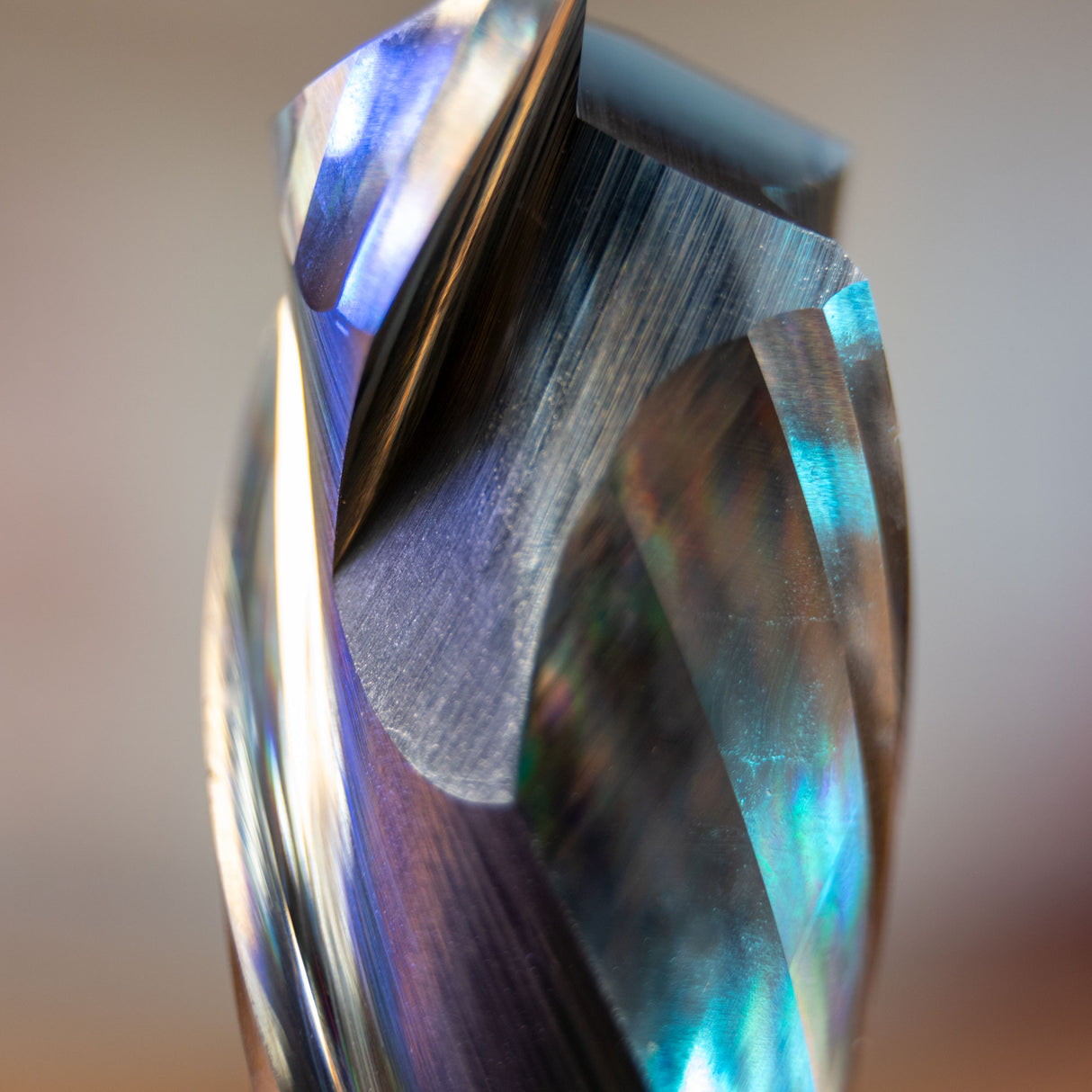 Close-up of a spiral compression plunge router bit with reflective fluted edges.