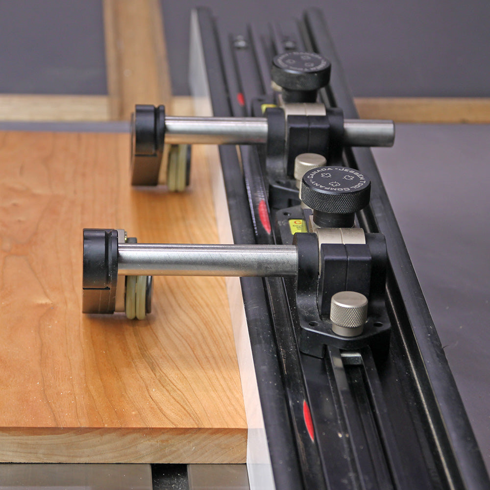 Router table fence with hold-down clamps securing wood for woodworking precision.