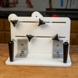 Vertical router sled with adjustable knobs and handles on a workbench in a workshop