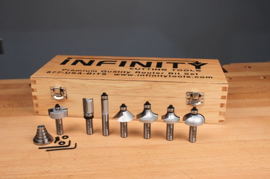 Premium woodworking router bit set with accessories in front of a wooden storage box on a workbench