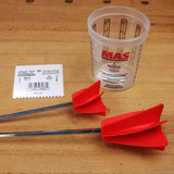 Woodworking epoxy mixing cup, red mixer paddles, and notched spreader on a workbench