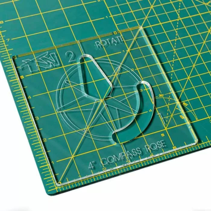 Acrylic compass rose template on green cutting mat with yellow measurement grid.