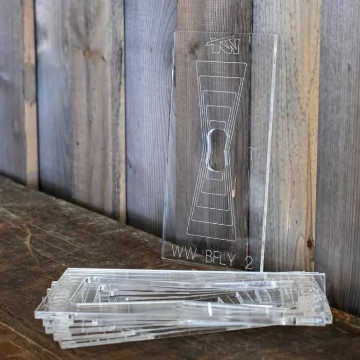 Clear acrylic butterfly key inlay template set on rustic wood surface, woodworking tool