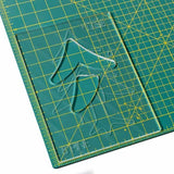 Acrylic woodworking template with tree shapes on a green cutting mat with yellow grid lines.