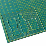 Clear acrylic cutting template with beverage bottle and glass shapes on a green grid mat.