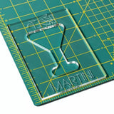 Acrylic martini glass template on a green cutting mat with yellow grid lines