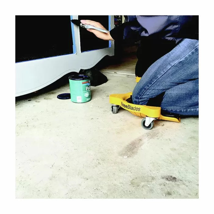Person using KneeBlades knee pads with wheels while painting furniture on a workshop floor