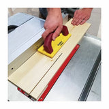 Woodworker using a safety push block to guide wood through a table saw