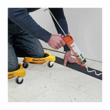 Person using a caulking gun while wearing yellow KneeBlades on tile flooring