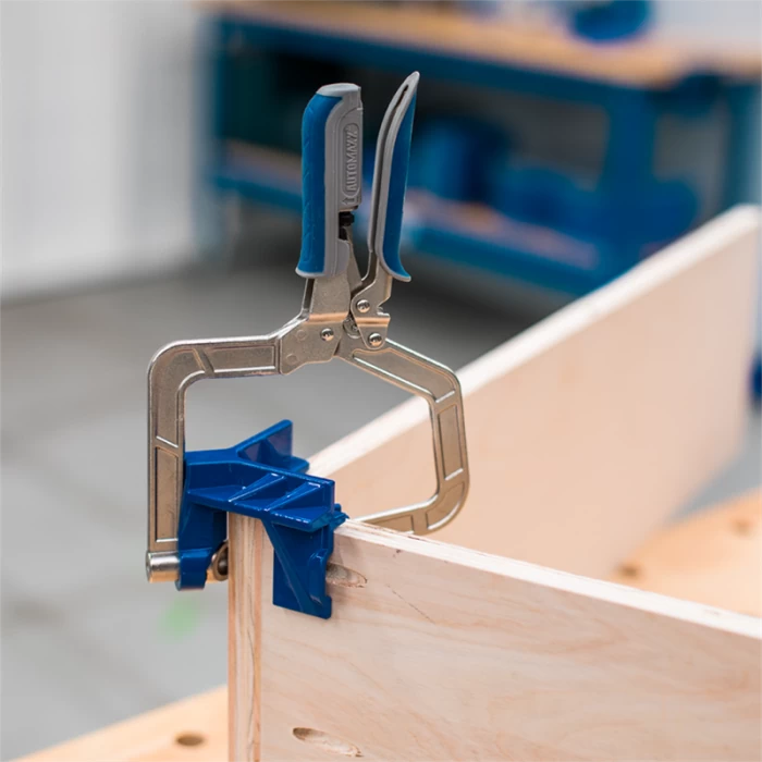 Corner clamp with blue handle securing wood boards for precise woodworking joints