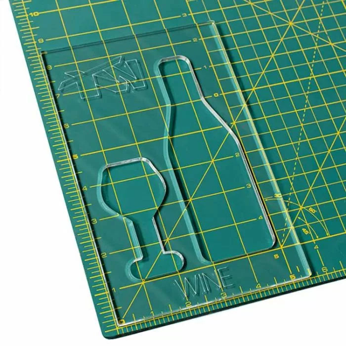 Acrylic wine bottle and glass template on green grid cutting mat for woodworking projects.