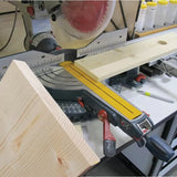 Miter saw cutting wood with a yellow fence system in a woodworking workshop setting.