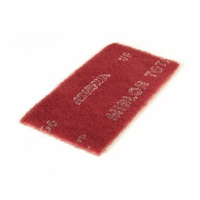 Maroon non-woven abrasive sanding pad for woodworking finishing tasks on white background