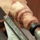 Close-up of a wooden spindle being shaped on a lathe with a bead detail