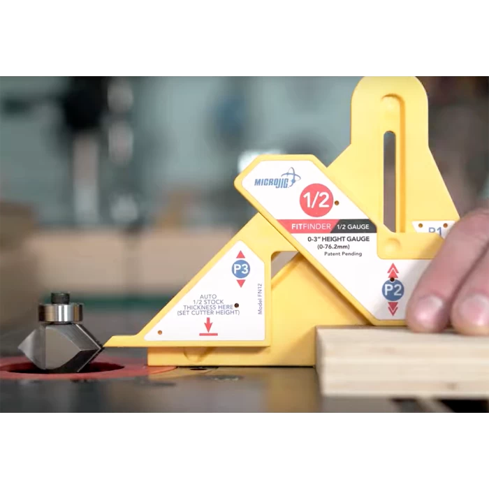 Woodworker using a yellow router table height gauge to set router bit and wood thickness