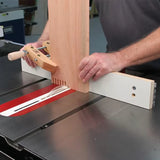 Woodworker using box joint jig on table saw with vertical board, creating precise finger joints.