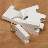 Set of white router setup blocks with measurement markings on a wooden surface