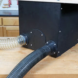 Woodworking dust collection box with attached flexible vacuum hoses on a workbench