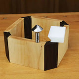 V-groove router bit with wooden hexagon box and plastic guide on a woodworking bench