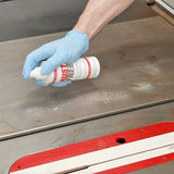 Applying rust remover spray to a metal table saw top for woodworking tool maintenance
