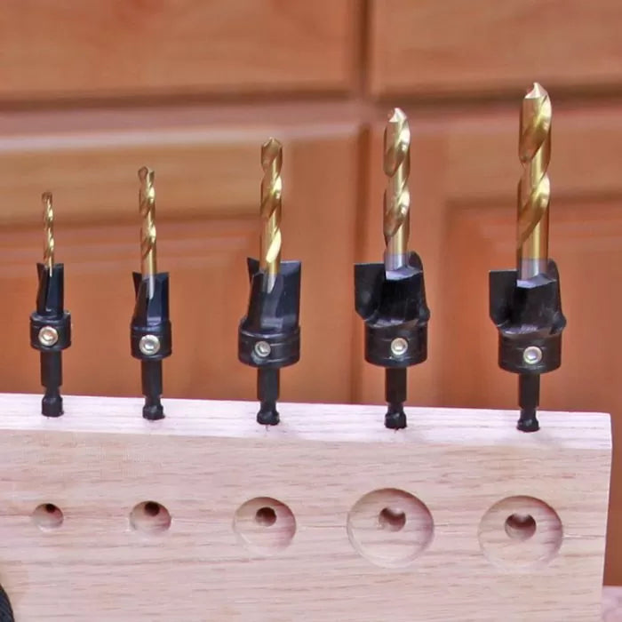 Set of woodworking drill bits with countersink cutters on a wooden board