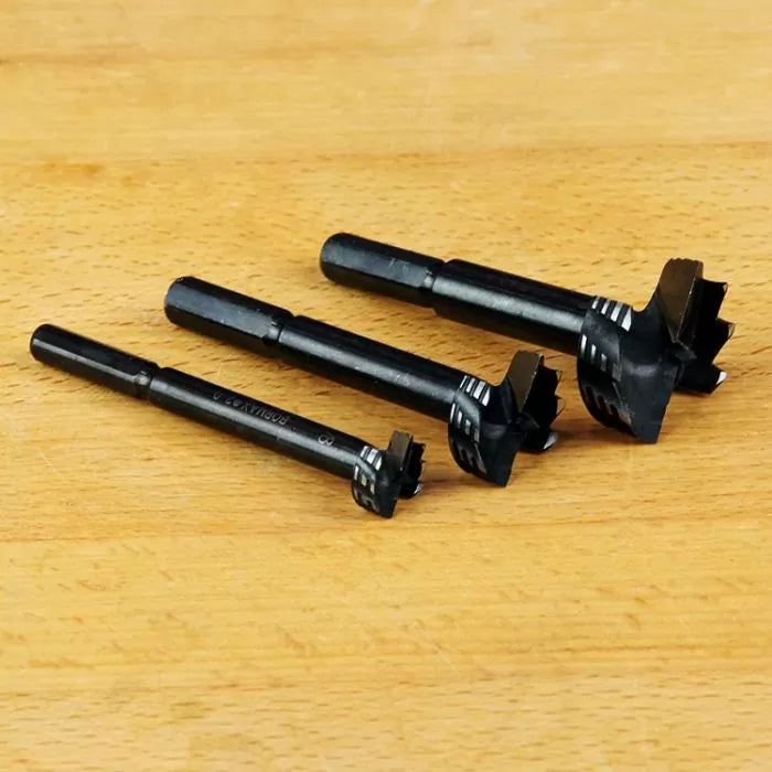 Set of three black woodworking Forstner drill bits on a wooden surface