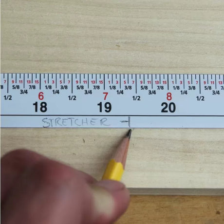 Measuring wood with tape measure and pencil marking a cut line for woodworking project
